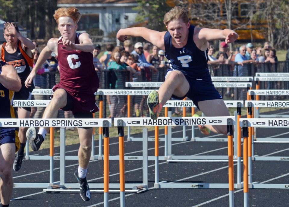 Petoskey's Luke Ingalls (right) clears a hurdle during the 110 meter event in Harbor Springs, followed by Charlevoix's Peyton Scott.