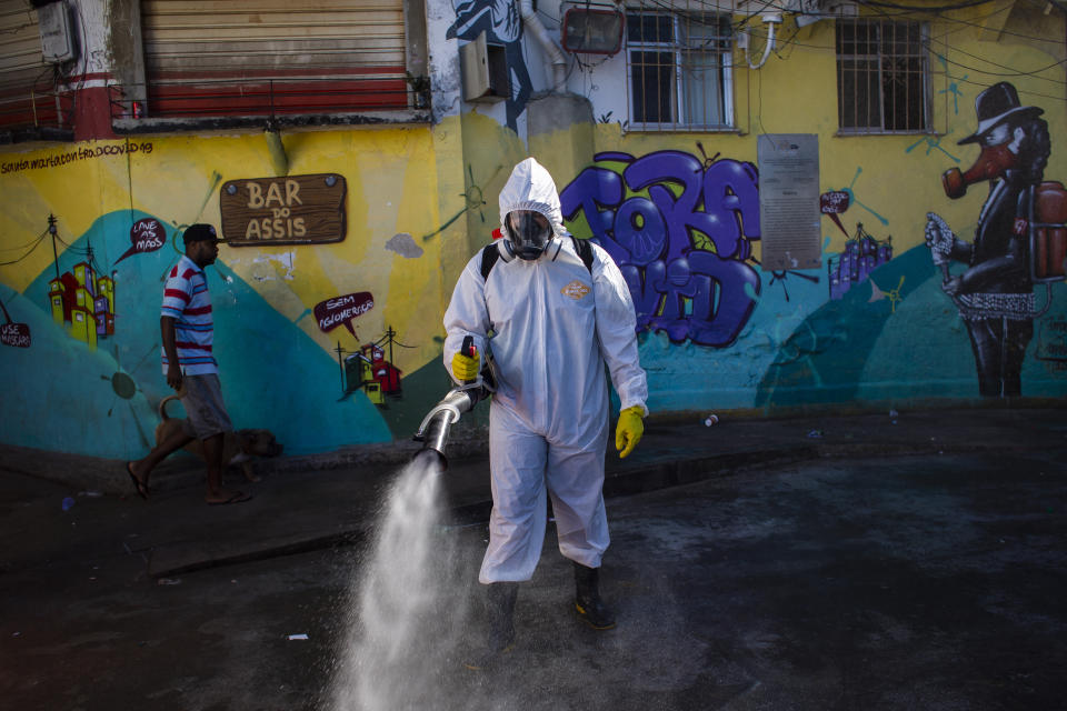 Thiago Firmino sprays disinfectant in an alley to help contain the spread of the new coronavirus, in the Santa Marta slum of Rio de Janeiro, Brazil, Saturday, April 24, 2021. (AP Photo/Bruna Prado)