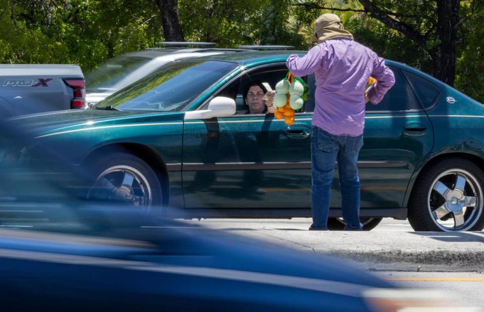 El vendedor ambulante Eddy Rivera vendiendo frutas y flores cerca de la intersección de Red Road y Northwest 135 St. el martes 2 de mayo de 2023, en Miami Lakes, la Florida.