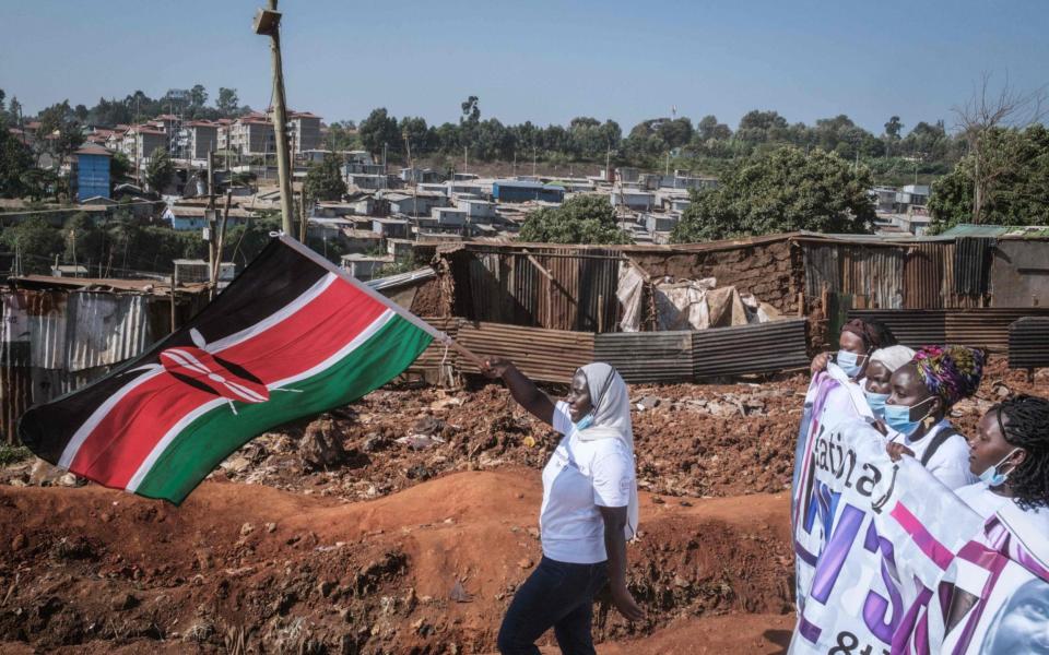 A woman waves the Kenyan flag during a IWD march - Yasuyoshi CHIBA / AFP