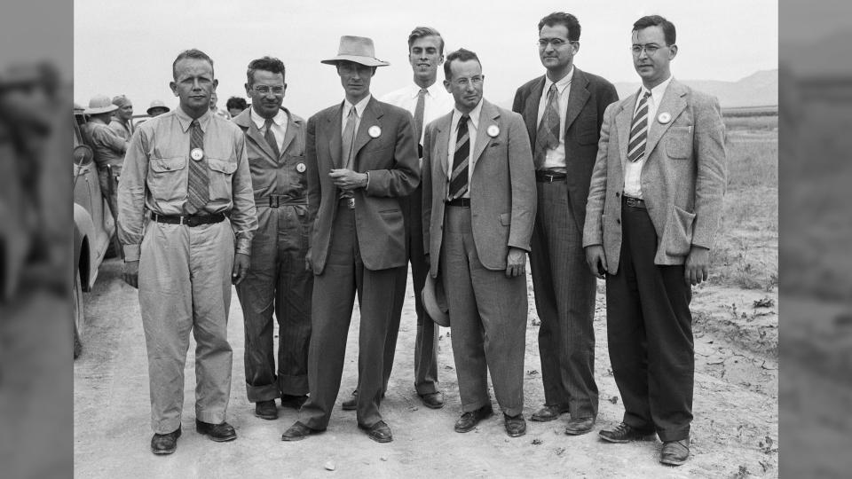 At a nuclear test site near Alamogordo, New Mexico, atomic bomb scientists measure radioactivity in seared sand particles 2 months after the explosion when newsmen saw bomb effects for the first time. Standing left to right: Dr. Kenneth.T. Bainbridge (Harvard University); Joseph G. Hoffman, (Buffalo, NY); Dr. J.R. Oppenheimer, Director of Los Alamos Atomic Bomb Project; Dr. L.H. Hempelman, (Washington University in St. Louis); Dr. R.F. Bacher (Cornell University); Dr. V.W. Weisskopf, (University of Rochester); and Dr. Richard W. Dodson (California). | Location: Near Alamogordo, New Mexico.