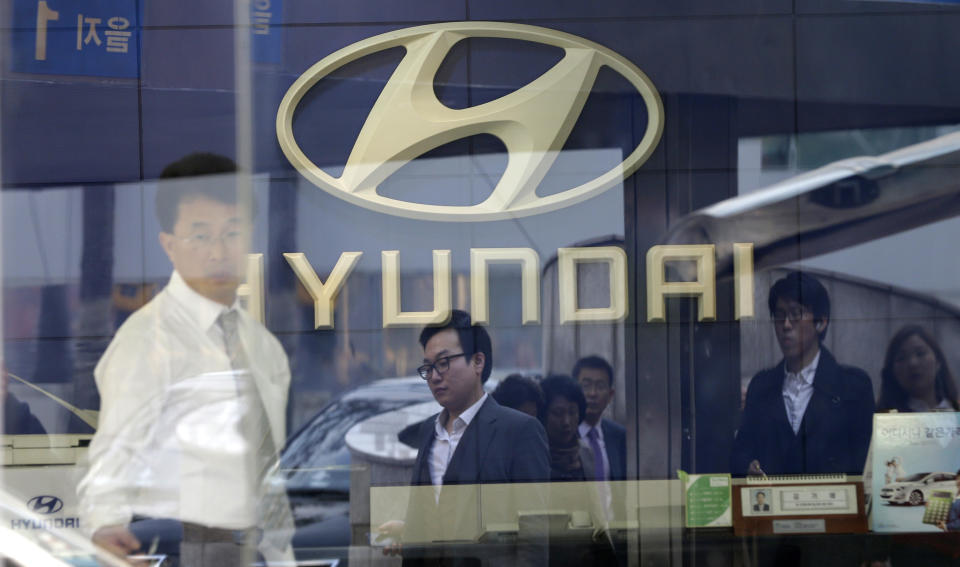 Pedestrians are reflected on the window of a Hyundai Motor's showroom in Seoul, South Korea, Thursday, Oct. 25, 2012. Hyundai Motor Co. suffered a fall in third quarter profit versus the previous quarter after strikes dented vehicle production. (AP Photo/Lee Jin-man)