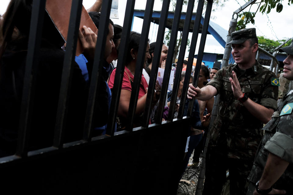 <p>A military officer (R) talks to Venezuelans as they queue to show their passports or identity cards at the Pacaraima border control, Roraima state, Brazil, Aug. 8, 2018. (Photo: Nacho Doce/Reuters) </p>