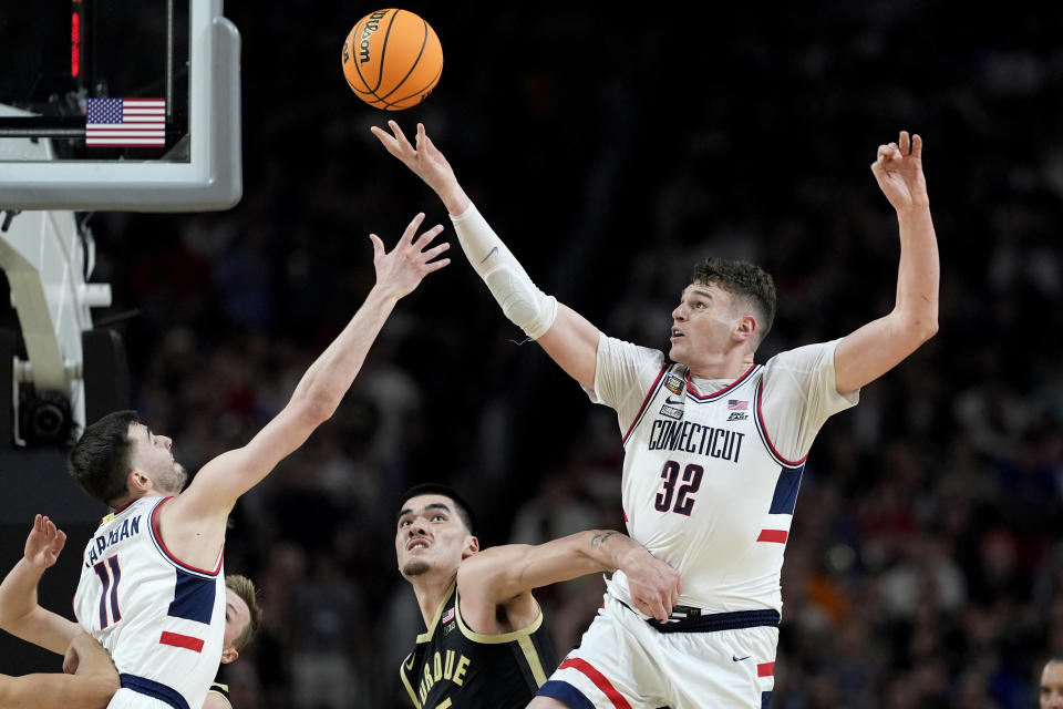 FILE - UConn center Donovan Clingan (32) reaches for the ball as Purdue center Zach Edey defends during the second half of the NCAA college Final Four championship basketball game, Monday, April 8, 2024, in Glendale, Ariz. Clingan is considered to be among the top prospects in this month’s NBA draft. (AP Photo/Brynn Anderson, File)