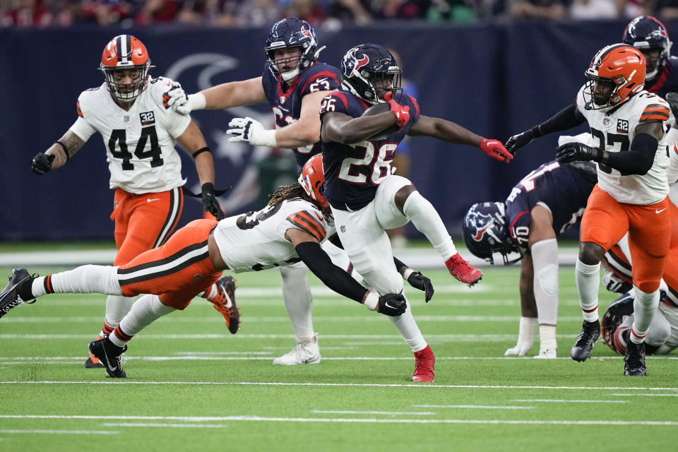 Houston Texans running back Devin Singletary (26) evades a tackle by Cleveland Browns safety Ronnie Hickman (33) during the first half of an NFL football game Sunday, Dec. 24, 2023, in Houston. (AP Photo/David J. Phillip)