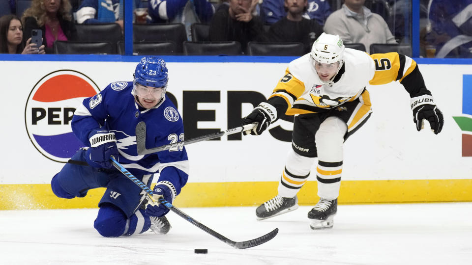 Tampa Bay Lightning center Michael Eyssimont (23) plays the puck from his knees after getting around Pittsburgh Penguins defenseman Ryan Shea (5) during the second period of an NHL hockey game Wednesday, Dec. 6, 2023, in Tampa, Fla. (AP Photo/Chris O'Meara)