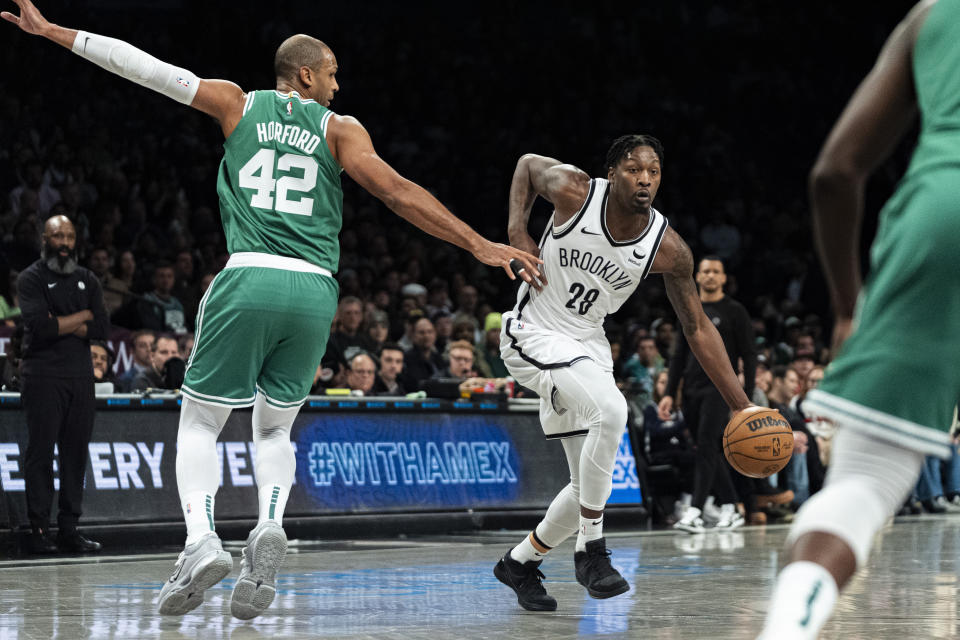 Brooklyn Nets forward Dorian Finney-Smith (28) drives to the basket against Boston Celtics center Al Horford (42) during the first half of an NBA basketball game in New York, Tuesday, Feb. 13, 2024. (AP Photo/Peter K. Afriyie)