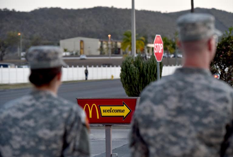 This photo made on April 8, 2014 in Guantanamo Bay naval base and Joint Detention Facility, Cuba, shows two US Army soldiers passing next to a McDonald's sign outside the chain's first and only restaurant on Cuban soil