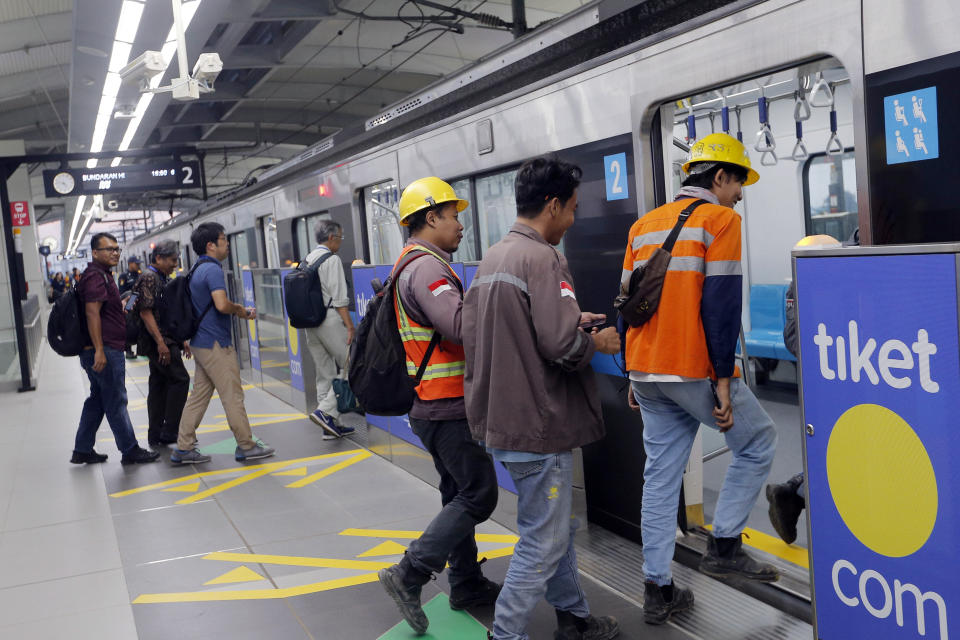 In this March 15, 2019, photo, passengers get on a Mass Rapid Transit (MRT) during a trial run in Jakarta, Indonesia. Commuting in the gridlocked Indonesian capital will for some involve less frustration, sweat and fumes when its first subway line opens later this month. The 10-mile system running south from Jakarta's downtown is the first phase of a development that if fully realized will plant a cross-shaped network of stations in the teeming city of 30 million people.(AP Photo/Tatan Syuflana)