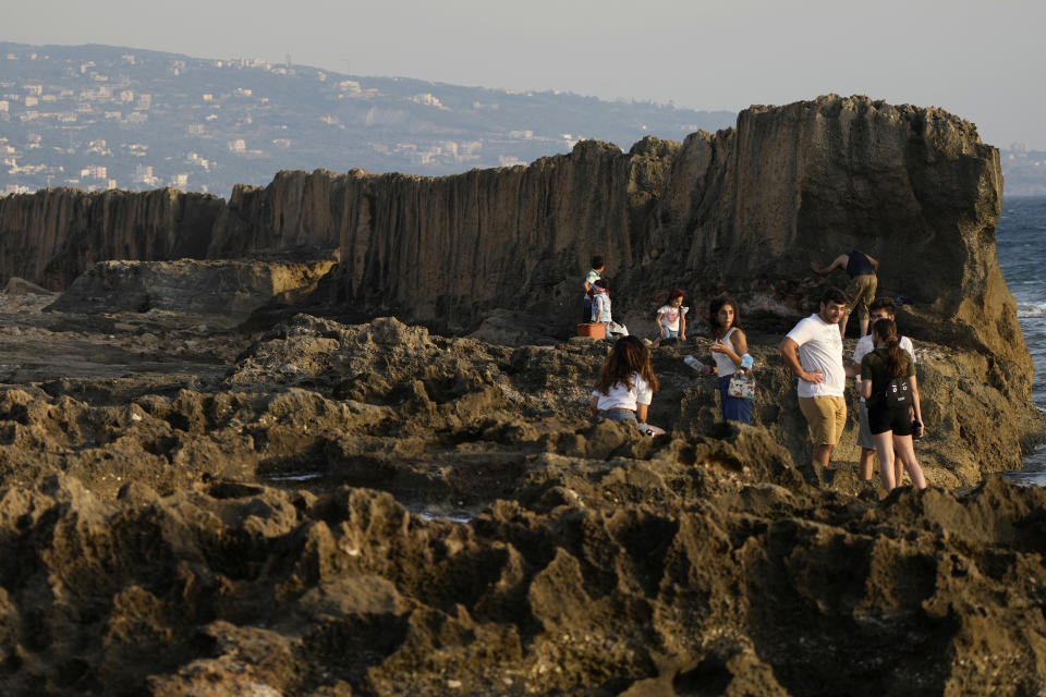 Residents walk near the Pheonician wall in Batroun village, north of Beirut, Lebanon, Friday, July 2, 2021. With their dollars trapped in the bank, a lack of functioning credit cards and travel restrictions imposed because of the pandemic, many Lebanese who traditionally vacationed over the summer at regional hotspots are also now turning toward domestic tourism. (AP Photo/Hassan Ammar)