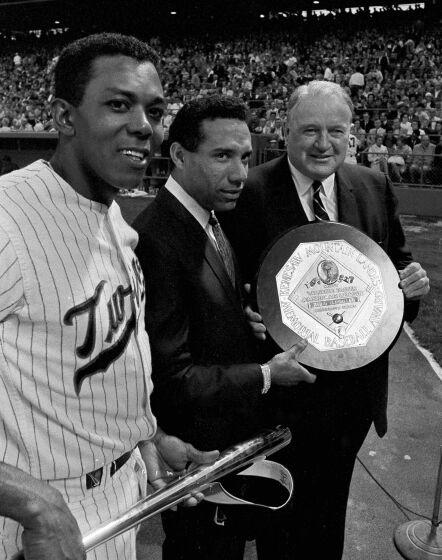 Three men stand on a baseball field