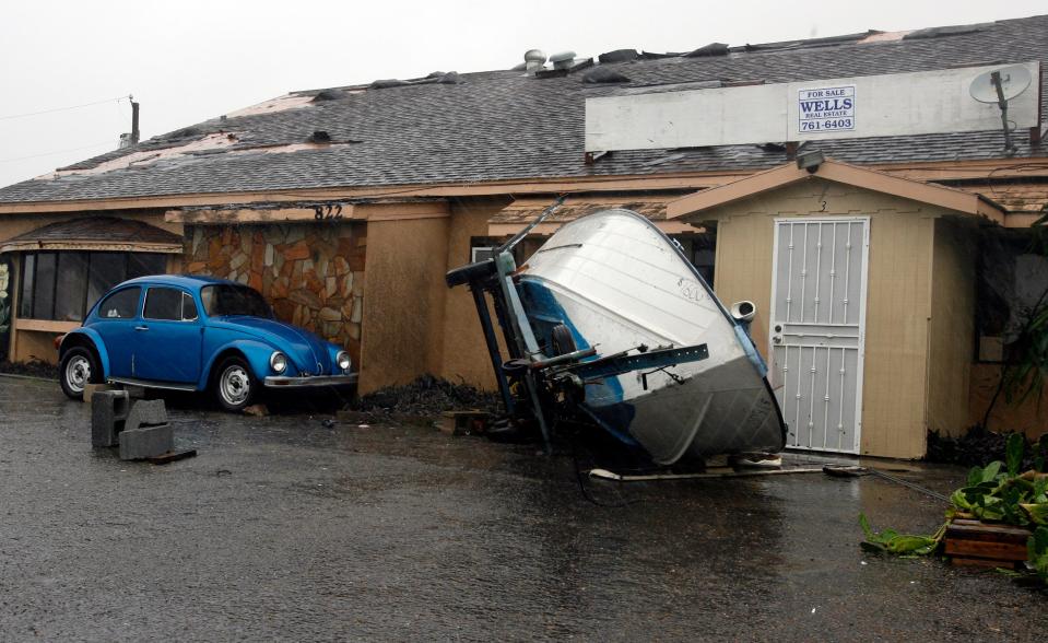 an upturned boat rests against a house from hurricane dolly damage in texas