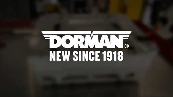 Dorman logo in front of an out-of-focus picture of a piece of machinery.