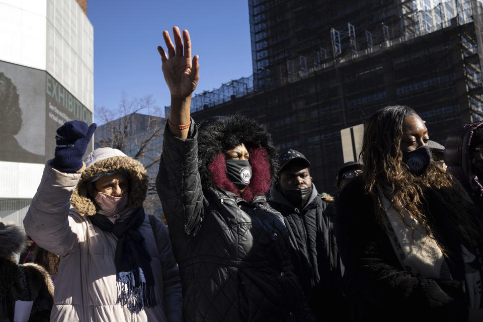 Members of the National Action Network raise their hands during a news conference near the scene of a shooting in Harlem the day before, Saturday, Jan. 22, 2022, in New York. (AP Photo/Yuki Iwamura)