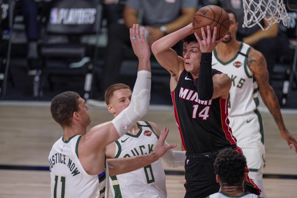 Miami Heat's Tyler Herro looks to pass past Milwaukee Bucks' Brook Lopez (11) and Donte DiVincenzo during the first half of an NBA conference semifinal playoff basketball game Sunday, Sept. 6, 2020, in Lake Buena Vista, Fla. (AP Photo/Mark J. Terrill)