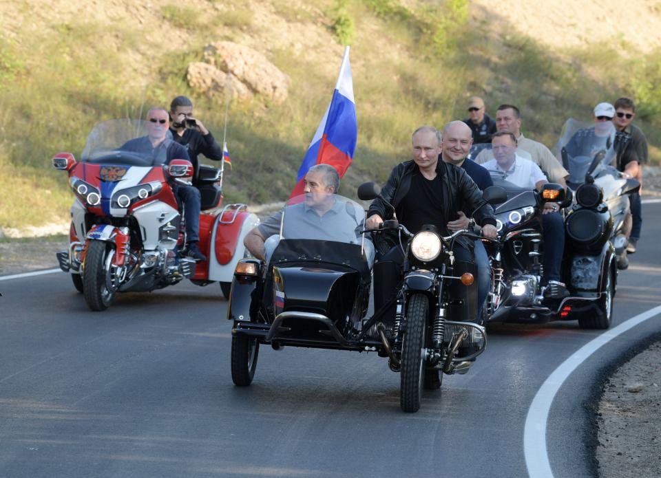 Russian President Vladimir Putin drives a motorbike, front, during the Babylon's Shadow bike show camp near in Sevastopol, Crimea, Saturday, Aug. 10, 2019. Head of the Republic of Crimea Sergei Aksenov, is in sidecar, and acting Governor of Sevastopol Mikhail Razvozhaev, rides pillion.(Alexei Druzhinin, Sputnik, Kremlin Pool Photo via AP)