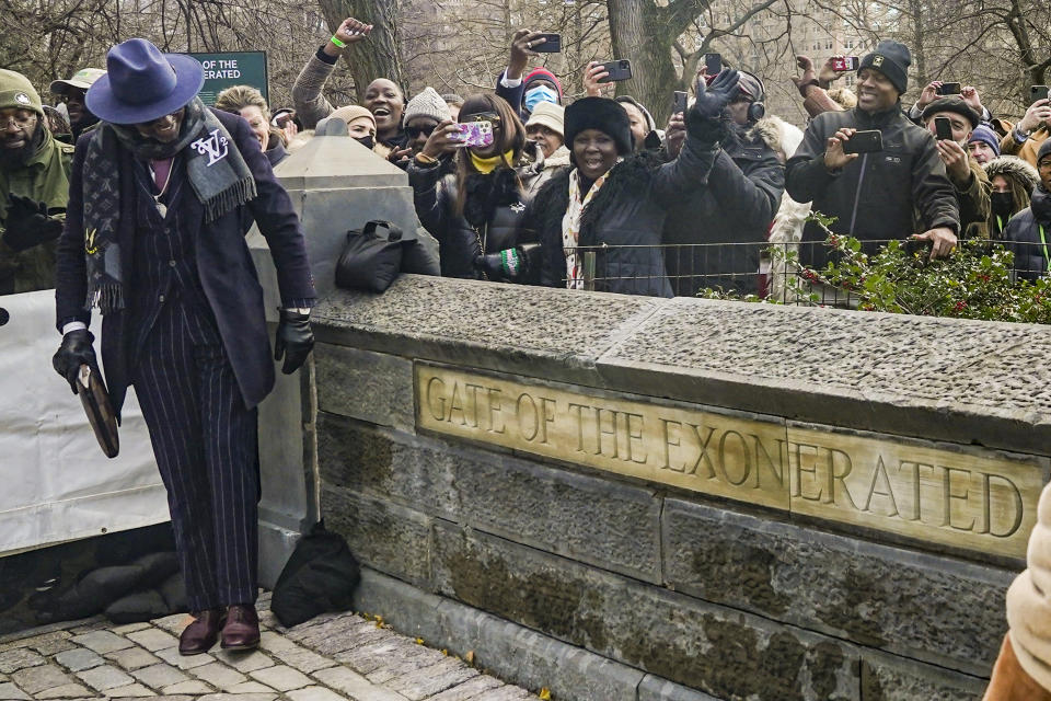 A crowd cheers as Yusef Salaam, left, one of five men exonerated after being wrongfully convicted as teenagers for the 1989 rape of a jogger in Central Park, looks at the plaque with the words "Gate of the Exonerated," unveiled during a naming ceremony for the northeast gateway of Central Park, Monday Dec. 19, 2022, in New York. The entrance was named to honor Salaam, Kevin Richardson, Raymond Santana Jr., Antron McCray, Korey Wise — the five men exonerated in the case. (AP Photo/Bebeto Matthews)