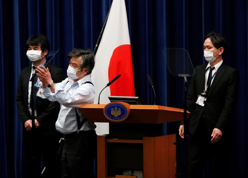 Officials wearing protective face masks, following an outbreak of the coronavirus, prepare a prompter before a news conference by Japan's Prime Minister Shinzo Abe at his official residence in Tokyo