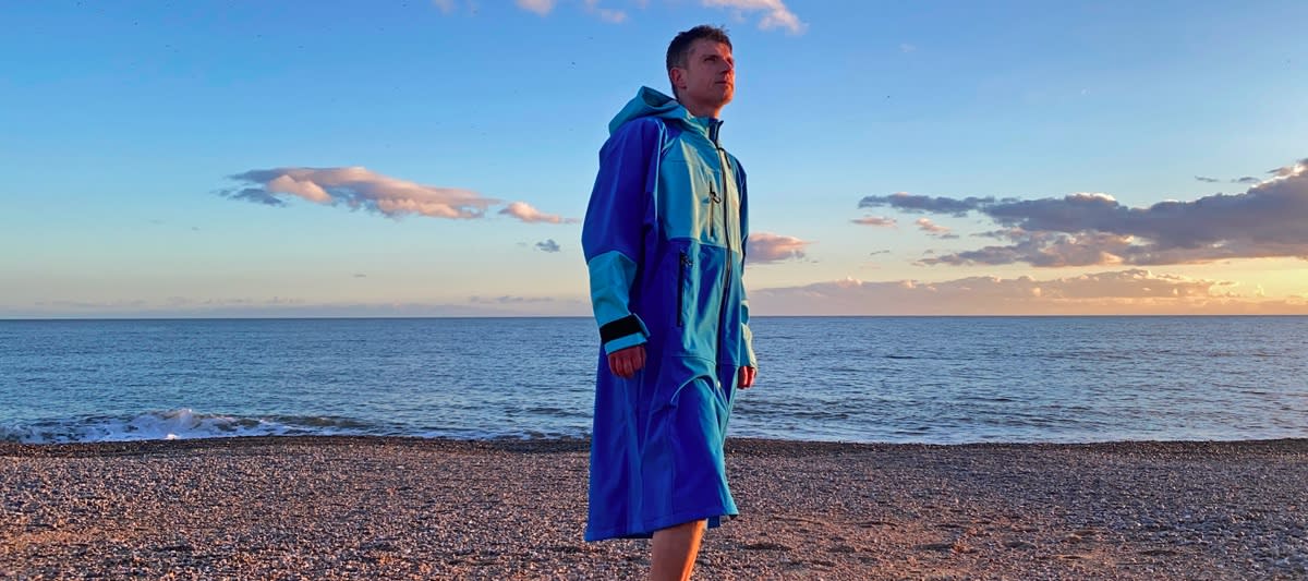  Man on beach wearing White Water Softshell Robe. 