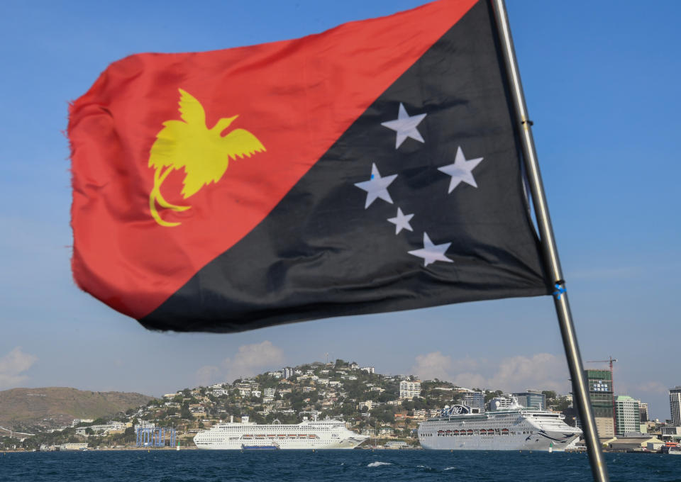 PORT MORESBY, PAPUA NEW GUINEA - NOVEMBER 13:  The national flag of PNG flies in front of P&O's Pacific Explorer (foreground) and Pacific Jewel berthed on November 13, 2018 in Port Moresby, Papua New Guinea. Highlighting Carnival Australia's long-standing committment to the Pacific and PNG, three of the company's ships are supporting PNG's successful hosting of APEC 2018 in the national capital with two of the ships already in port to be joined by Princess Cruises' Sea Princess on Wednesday. It is seen as a natural extension of the company's local cruise activity making 250 port calls from 2016-2018 bringing 400,000 visitors to PNG.  (Photo by James D. Morgan/Getty Images for Carnival Australia)
