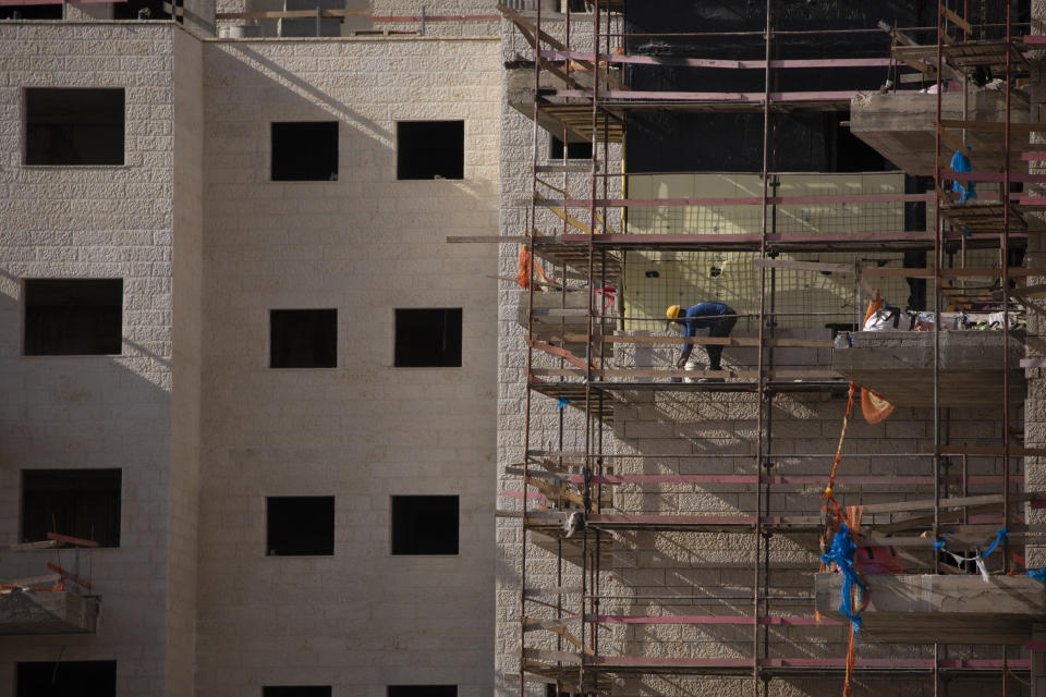 A Palestinian laborer works on a new building in the West Bank Jewish settlement of Efrat, Tuesday, March 16, 2021. Israel went on an aggressive settlement spree during the Trump era, according to an AP investigation, pushing deeper into the occupied West Bank than ever before and putting the Biden administration into a bind as it seeks to revive Mideast peace efforts. (AP Photo/Maya Alleruzzo)