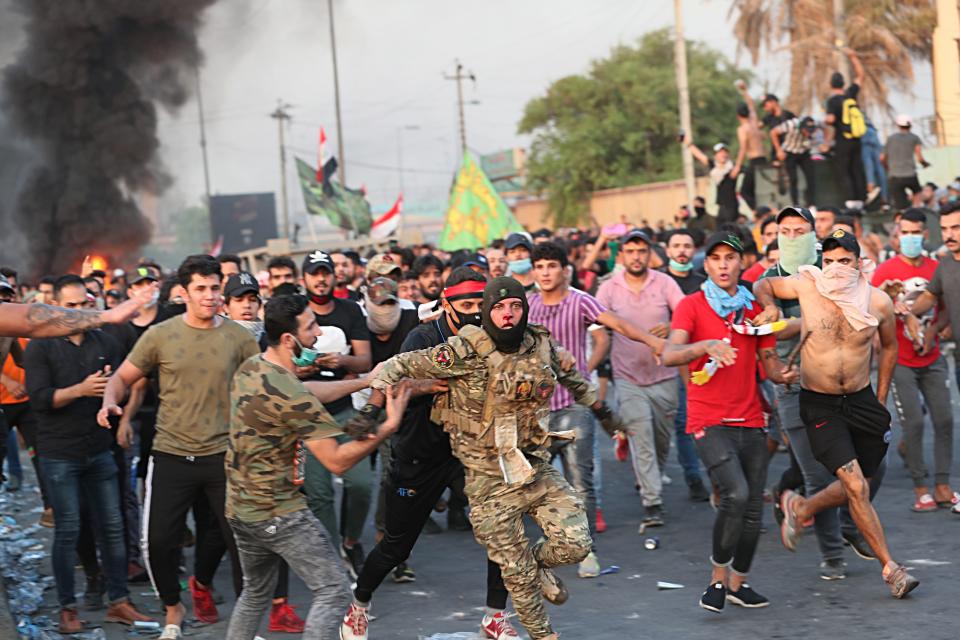 Anti-government protesters help a soldier from the Federal Police Rapid Response Forces to get out of the protest site area after other protesters beat him, in Baghdad, Iraq, Thursday, Oct. 3, 2019. Iraqi security forces fired live bullets into the air and used tear gas against a few hundred protesters in central Baghdad on Thursday, hours after a curfew was announced in the Iraqi capital on the heels of two days of deadly violence that gripped the country amid anti-government protests that killed over 19 people in two days. (AP Photo/Hadi Mizban)