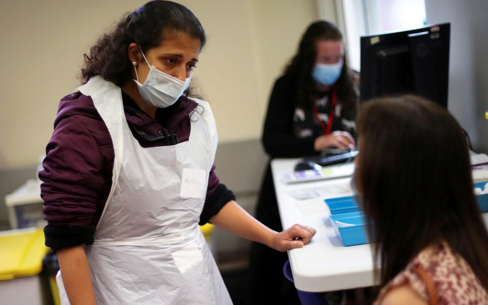 A health worker speaks to a woman as healthcare staff receive Covid-19 booster jabs at Midland House in Derby on 20 September 2021 - Carl Recine/Reuters