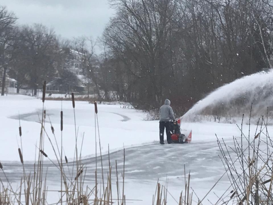 A volunteer removes snow from a frozen Humboldt Park lagoon, which is used for hockey and ice skating.