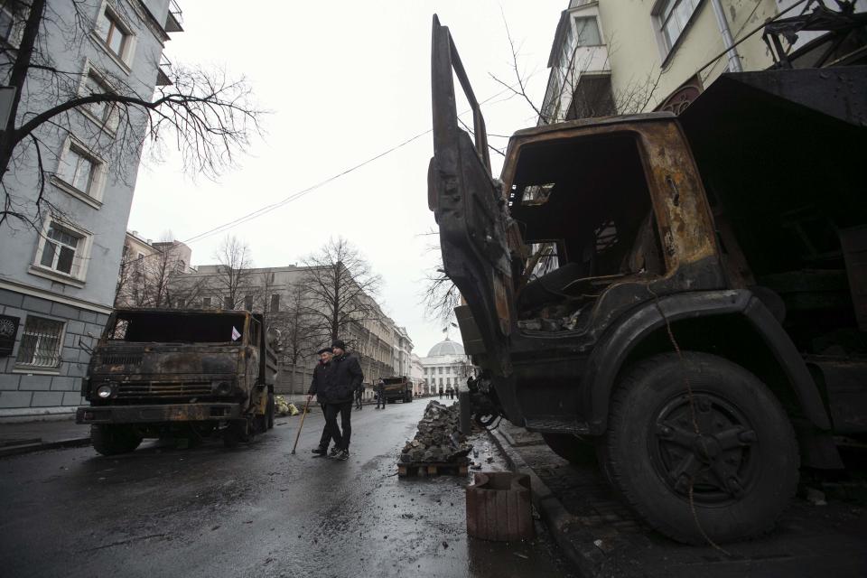 A man walks past burnt trucks near parliament house in Kiev