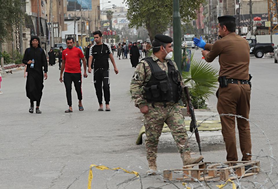 Security forces warn Shiite Pilgrims marching too the shrine of Imam Moussa al-Kadhim, a key Shiite saint, during preparations for the annual commemoration of his death, in Baghdad, Iraq Friday, March 20, 2020. Iraq announced a weeklong curfew to help fight the spread of the virus. For most people, the virus causes only mild or moderate symptoms. For some it can cause more severe illness. (AP Photo/Hadi Mizban)