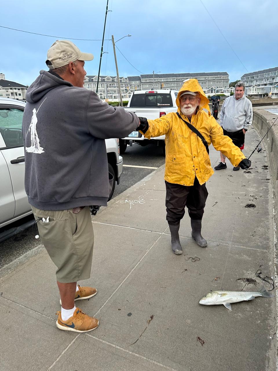 David “Hard Tail” Taylor, left, gets a fist-bump from fellow fisherman Robert Shaw after hauling in a striped bass over the wall at Narragansett Town Beach as Hurricane Lee passed by on Saturday morning.