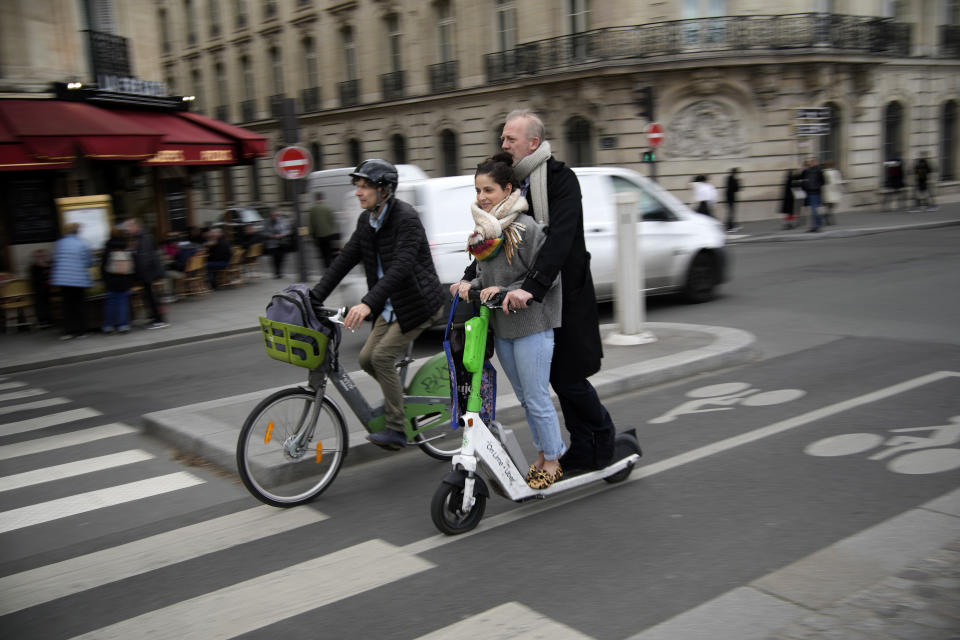 Tourists ride a scooter in Paris, Friday, march 31, 2023. Romantically zipping two-to-a-scooter, wind in the hair, past the Eiffel Tower and other iconic sights could soon become a thing of the past if Parisians vote Sunday to do away with the 15,000 opinion-dividing micro-machines. (AP Photo/Christophe Ena)