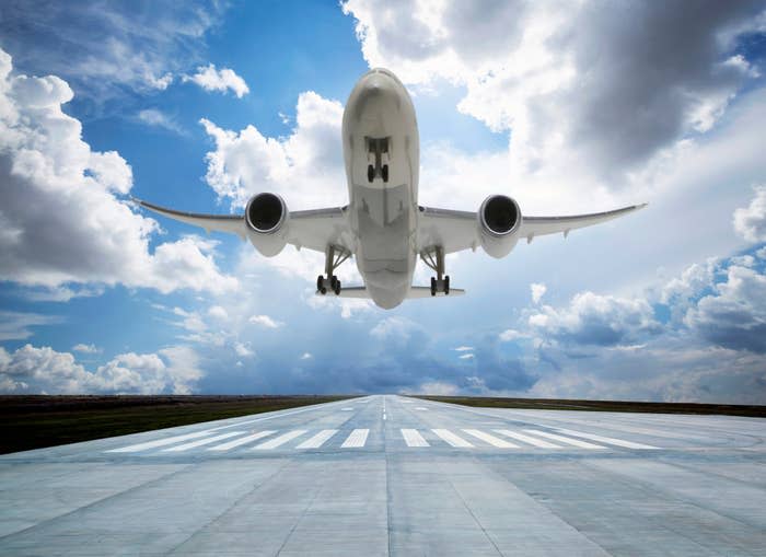 An airplane takes off from a runway under a cloudy sky