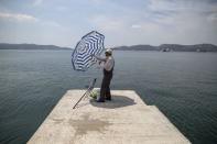 A fisherman adjusts a sun umbrella in the town of Elefsina, near Athens, Greece June 30, 2015. REUTERS/Marko Djurica