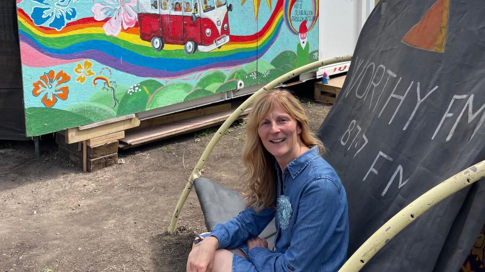 Women sat on chair with Worthy FM sign behind her