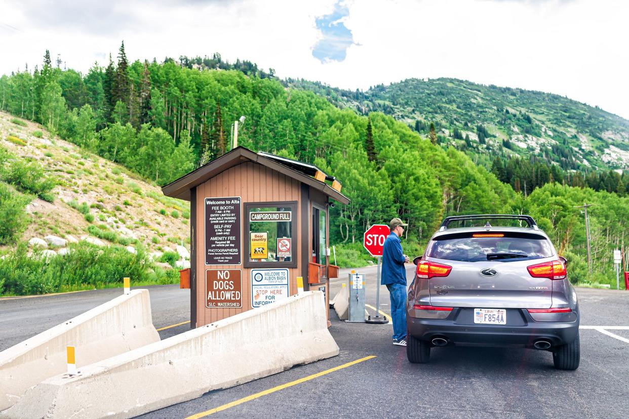 Alta, USA - July 25, 2019: Entrance with information sign to national park hiking trails in Albion Basin, Utah summer in Wasatch mountains and campground with man employee worker