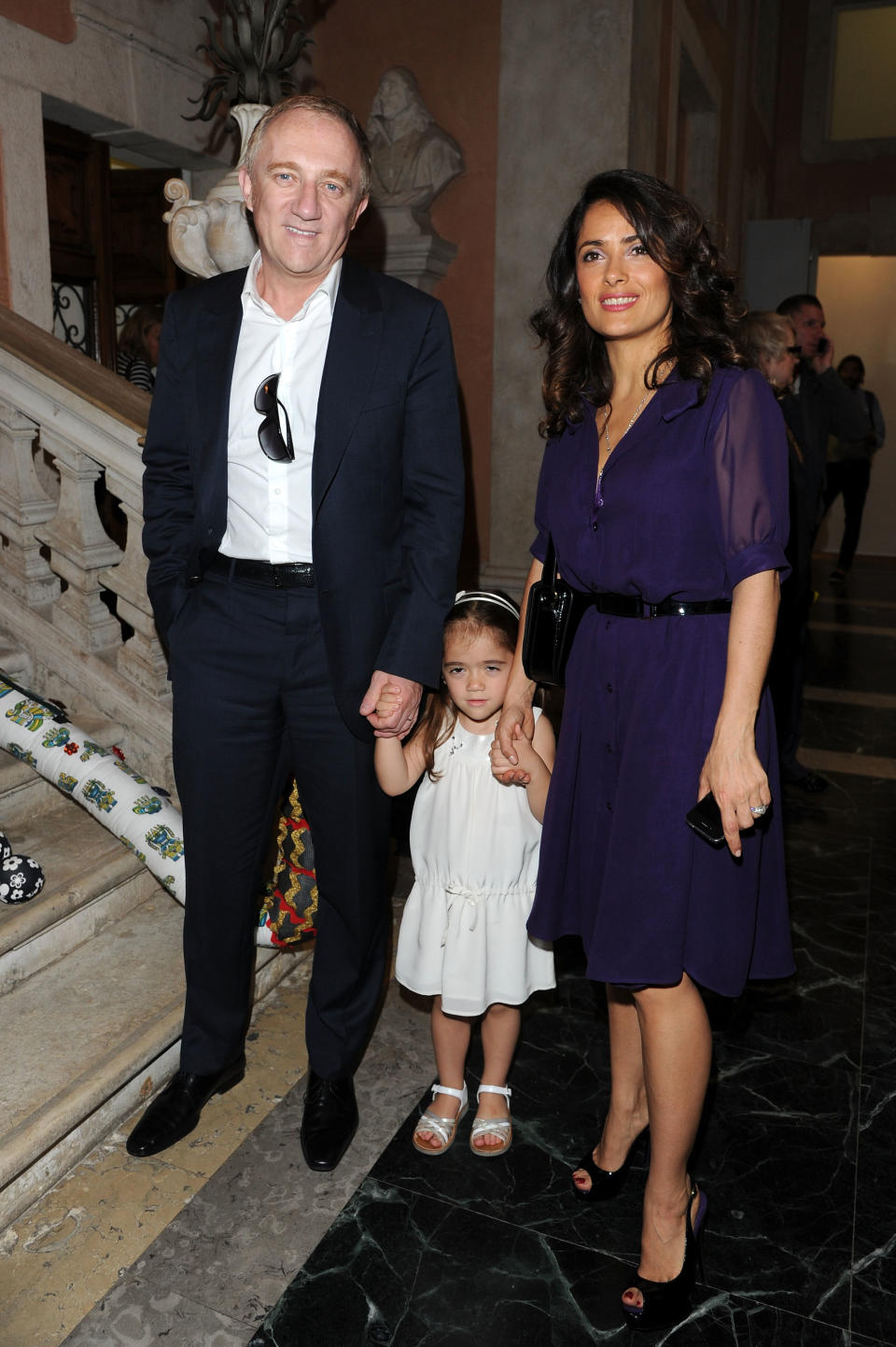 Salma and François-Henri hold hands with a young Valentina