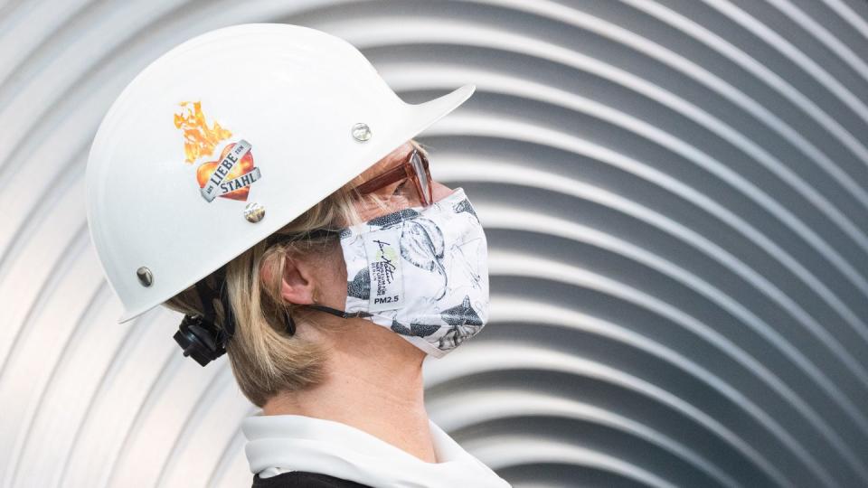 Anja Karliczek, Bundesministerin für Bildung und Forschung, trägt einen Mund-Nasenschutz und einen Helm im Werk der Salzgitter AG.