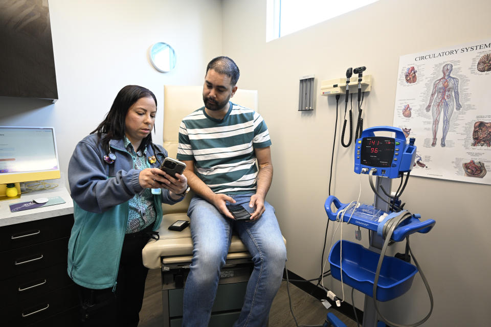 La enfermera Eliza Otero (izq.) habla con Fernando Hermida durante su visita a Pineapple Healthcare en Orlando, Florida, el 28 de mayo de 2024. La clínica atiende a una población LGBTQ+, especialmente a latinos que viven con VIH. (Foto: AP/Phelan M. Ebenhack)