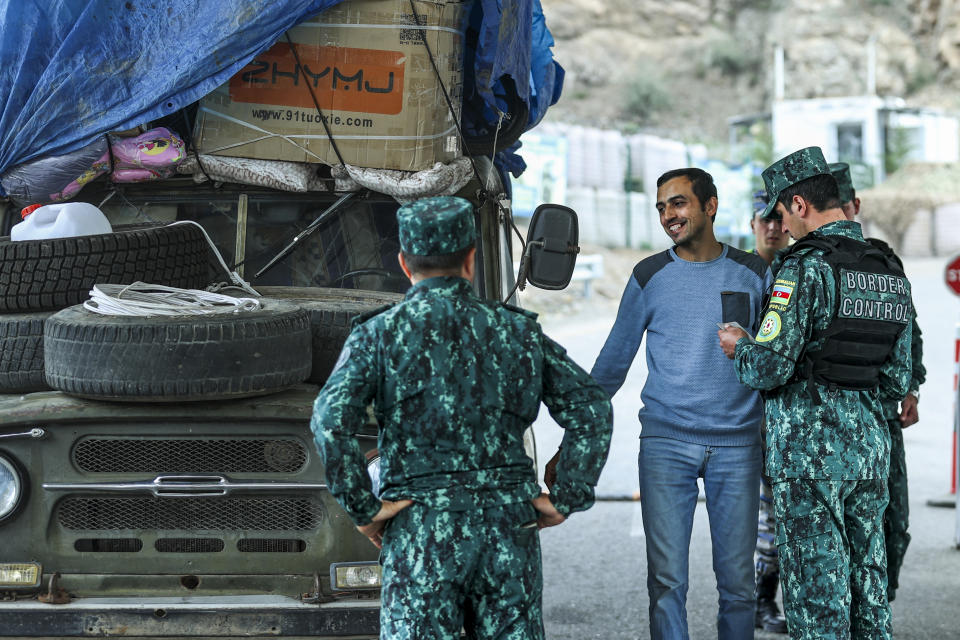 Sergey Astsetryan, an ethnic Armenian resident of Nagorno-Karabakh, center behind a serviceman, smiles as he shows his belongings as Azerbaijani border guard servicemen check his Soviet-made vehicle at the Lachin checkpoint on the way from Nagorno-Karabakh to Armenia, in Azerbaijan, Sunday, Oct. 1, 2023. Astsetrayn was one of the last residents of Nagorno-Karabakh to drive out of the region in his own vehicle as part of a grueling weeklong exodus of over 100,000 people — more than 80% of the residents — after Azerbaijan reclaimed the area in a lightning military operation. (AP Photo/Aziz Karimov)