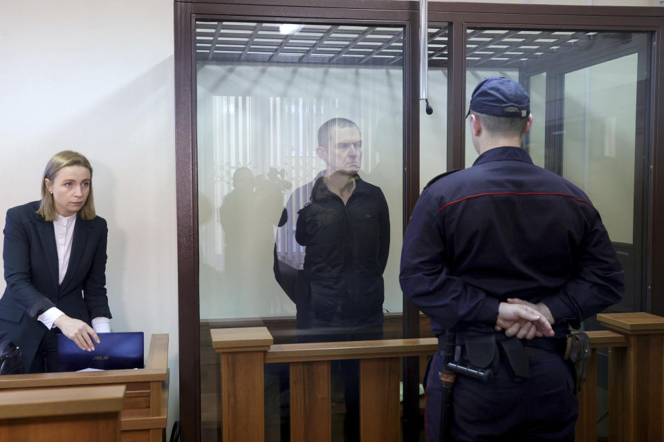 Journalist Andrzej Poczobut, center, stands in a defendants' cage during a court session in Grodno, Belarus, Monday, Jan. 16, 2023. Belarus on Monday opened the trial of a journalist and prominent member of the country's sizable Polish minority, the latest in a series of court cases against critics of the authoritarian regime of President Alexander Lukashenko. (Leonid Shcheglov/Pool via AP)