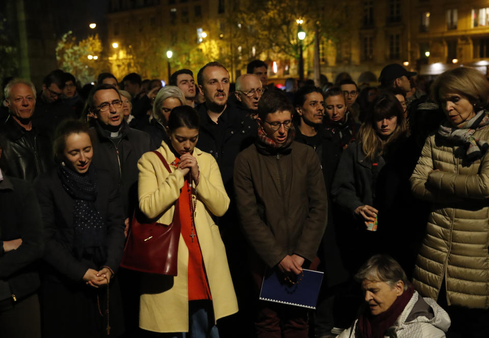 People pray as Notre Dame cathedral is burning in Paris, April 15, 2019. A catastrophic fire engulfed the upper reaches of Paris' soaring Notre Dame Cathedral as it was undergoing renovations Monday, threatening one of the greatest architectural treasures of the Western world as tourists and Parisians looked on aghast from the streets below. (Photo: Christophe Ena/AP)