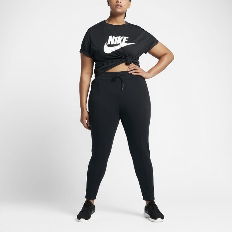 A model wears a black Nike T-shirt, black sweatpants, and black running shoes.