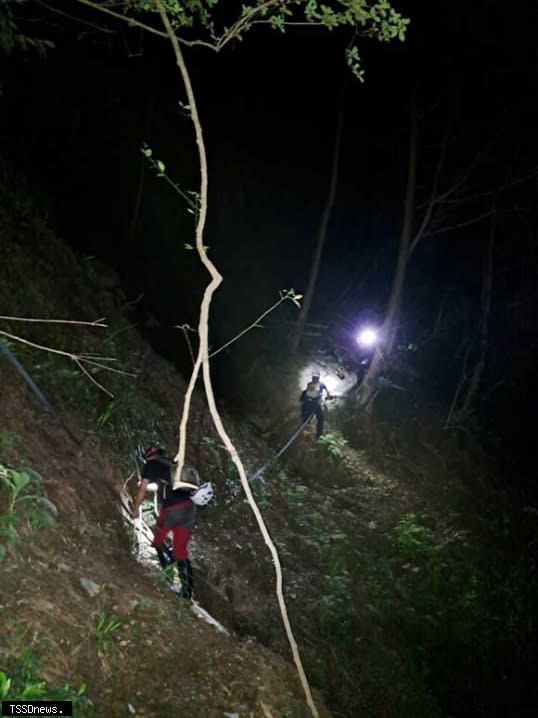 萬大南溪第四匯流口登山客遭溪水沖走事故，一死一傷，搜救人員落夜將受傷李姓山友護送下。(南投縣府消防局提供)