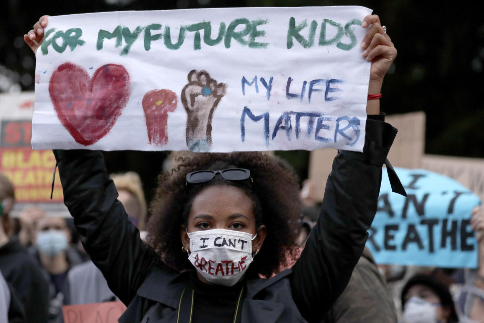 A woman holds a sign as protesters gather in Sydney, Tuesday, June 2, 2020, to support the cause of U.S. protests over the death of George Floyd and urged their own governments to address racism and police violence. Floyd died last week after he was pinned to the pavement by a white police officer who put his knee on the handcuffed black man's neck until he stopped breathing. (AP Photo/Rick Rycroft)