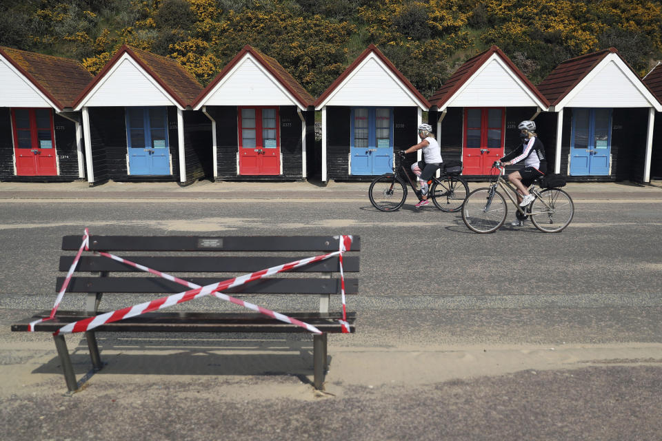 Cyclists make their way past a taped off bench on the sea front area at Bournemouth beach, as the UK continues in lockdown to help curb the spread of the coronavirus, in Bournemouth, England, Friday April 10, 2020. Many public recreation facilities have been closed off due to coronavirus. The highly contagious COVID-19 coronavirus has impacted on nations around the globe, many imposing self isolation and exercising social distancing when people move from their homes. (Andrew Matthews / PA via AP)