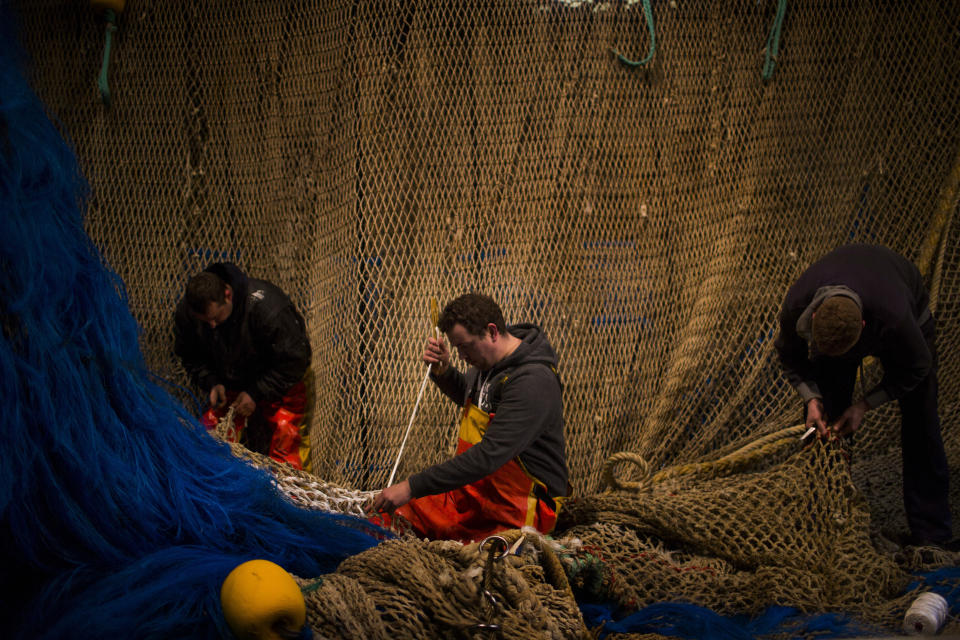 FILE- In this Friday, March 3, 2017 file photo, fishermen of the Maarten-Jacob ship work fixing their fishing net at the port in The Hague, The Netherlands. Fishing has become one of the main stumbling blocs in the Brexit negotiations for a new trade deal between the European Union and the United Kingdom. (AP Photo/Emilio Morenatti, File)