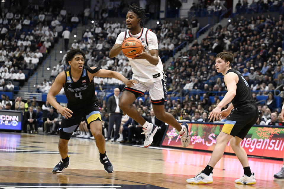 UConn guard Tristen Newton looks to pass between Marquette guard Stevie Mitchell, left, and Marquette guard Tyler Kolek, right, in the first half of an NCAA college basketball game, Saturday, Feb. 17, 2024, in Hartford, Conn. (AP Photo/Jessica Hill)