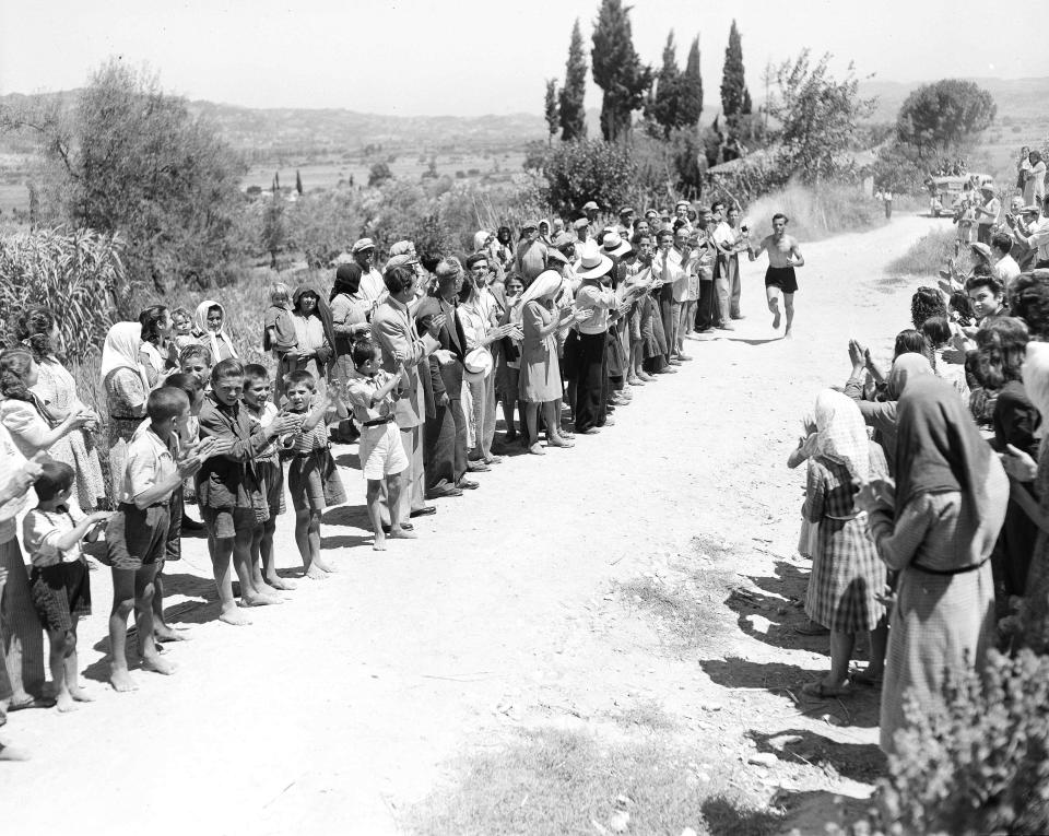 FILE - Villagers in Strefi, Greece, cheer a runner carrying the Olympic flame in the relay from Olympia to Pyrgos, July 20, 1948. On Tuesday, April 16, 2024 the flame for this summer's Paris Olympics will be lit and be carried through Greece for more than 5,000 kilometers (3,100 miles) before being handed over to French organizers at the Athens site of the first modern Olympics. (AP Photo, File)