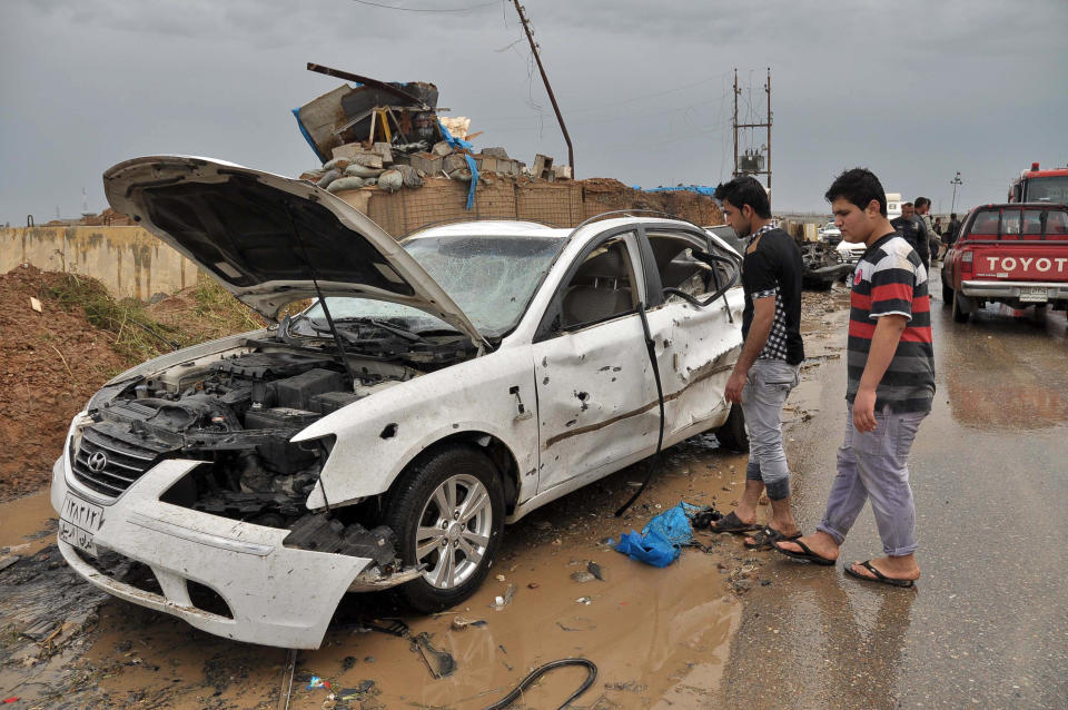 Iraq civilians inspect the site of a suicide car bombing in the northern town of Dibis, near the city of Kirkuk, 290 kilometers (180 miles) north of Baghdad, Iraq, Sunday, April 13, 2014. A suicide bomber rammed his explosives-laden car into a security checkpoint, killing and wounding policemen and civilians, authorities said. (AP Photo/Emad Matti)